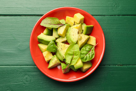 Tasty cut avocados with spinach and dressing on green wooden table, top viewの写真素材