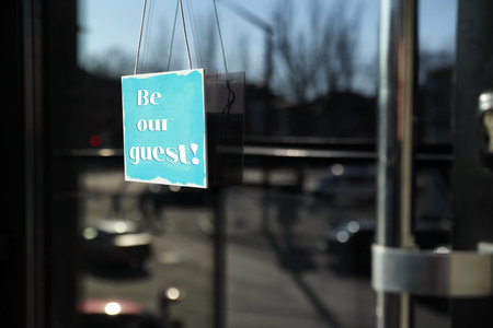 Be Our Guest sign hanging on glass door outdoors
