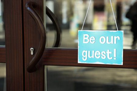 Be Our Guest sign hanging on glass door outdoorsの写真素材