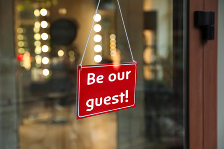 Be Our Guest sign hanging on glass door outdoorsの写真素材