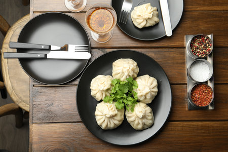 Delicious khinkali served with cilantro and wine on wooden table, flat layの写真素材