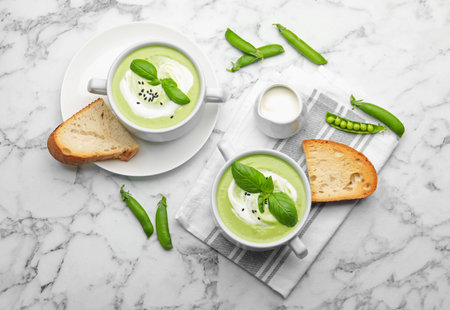 Tasty pea cream soup with basil served on white marble table, flat layの写真素材