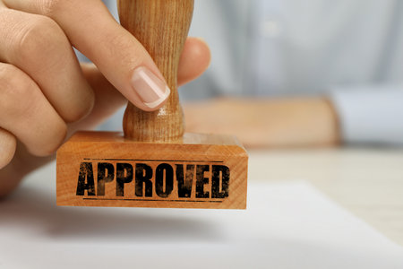 Approved. Woman stamping blank sheet of paper at table, closeupの写真素材