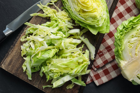 Cut fresh green cabbage and knife on black table, flat layの写真素材