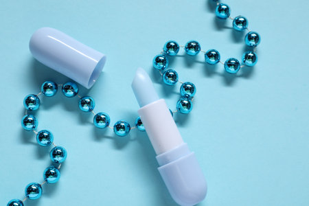 Moisturizing lip balm and Christmas decor on light blue background, flat lay. Winter careの写真素材