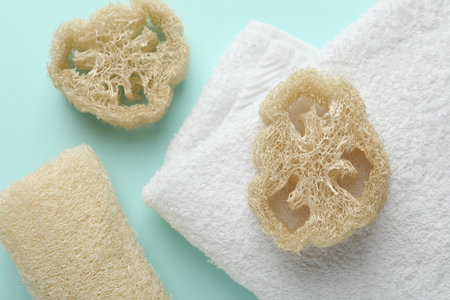 Natural loofah sponges and towel on light blue background, flat layの写真素材