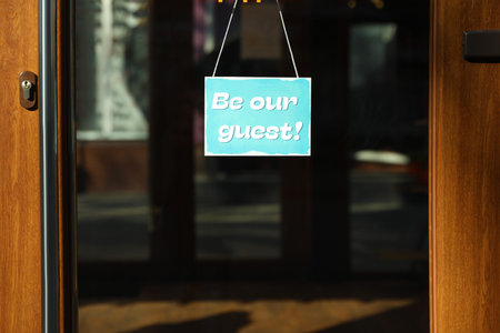 Be Our Guest sign hanging on glass door outdoorsの写真素材