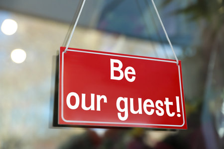 Be Our Guest sign hanging on glass outdoorsの写真素材