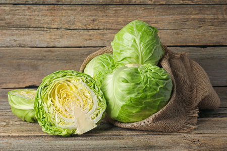 Fresh whole and cut cabbages on wooden tableの写真素材