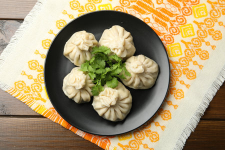 Delicious khinkali served with cilantro on wooden table, top view