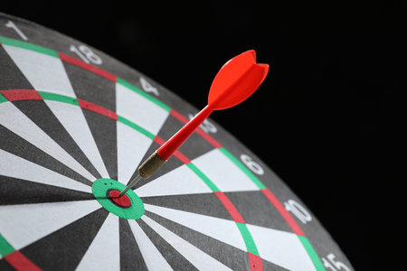 Targeting. Dart board with arrow on black background, closeupの写真素材
