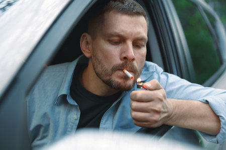Man lighting cigarette in car, view from outsideの写真素材