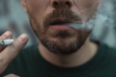 Man smoking cigarette on blurred background, closeup