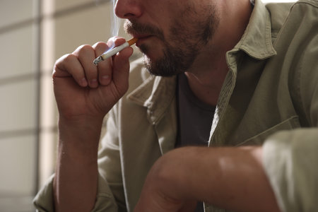 Man smoking cigarette on blurred background, closeup