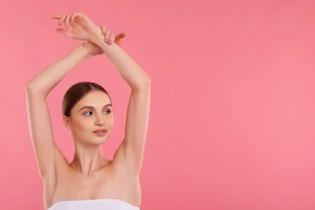 Young woman showing smooth skin after epilation on pink background, space for textの写真素材