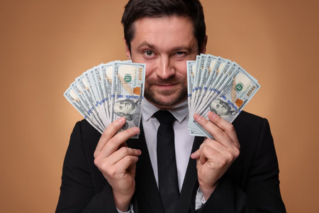 Greedy banker with dollar banknotes on golden background, closeupの写真素材