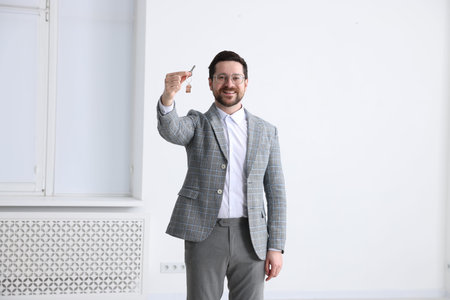 Real estate agent holding key with house shaped keychain indoorsの写真素材