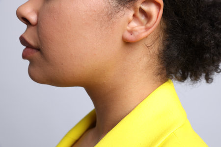 Young woman with pierced ear on light grey background, closeupの写真素材