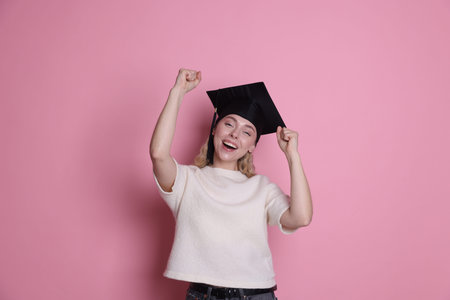 Happy student after graduation on pink background