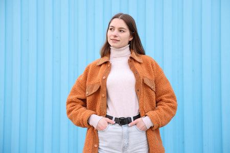 Portrait of teenage girl near light blue wall