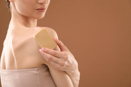 Woman with soap bar on brown background, closeup. Space for textの写真素材