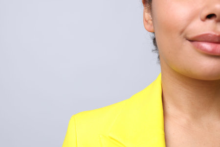 Young woman with pierced ear on light grey background, closeup. Space for textの写真素材