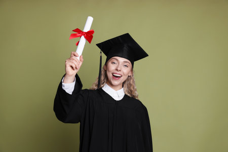Happy student with diploma after graduation on green backgroundの写真素材