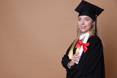 Happy student with diploma after graduation on beige background. Space for text