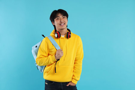 Student with headphones and backpack on light blue backgroundの写真素材
