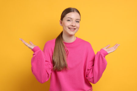 Portrait of teenage girl on yellow backgroundの写真素材