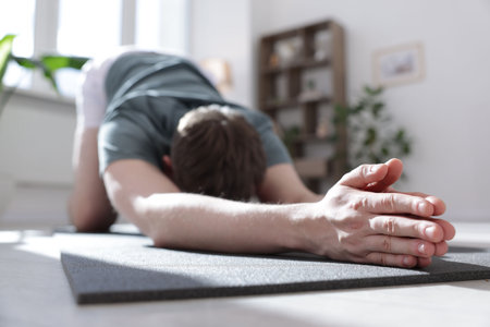 Young man practicing yoga at home, closeup
