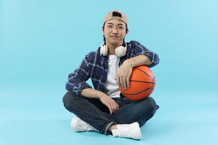 Student with headphones and basketball ball on light blue backgroundの写真素材
