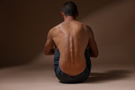 Man suffering from anorexia on beige background, back viewの写真素材