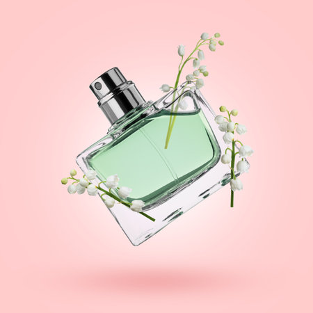 Lilies of the valley and bottle of perfume in air on pink backgroundの写真素材