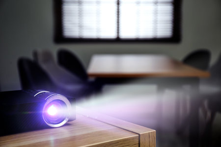 Modern video projector working on wooden table indoorsの写真素材