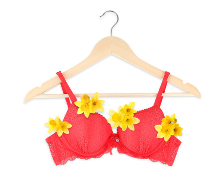 Beautiful red bra with daffodil flowers on wooden hanger against white backgroundの写真素材