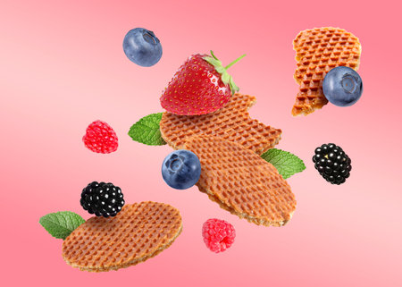 Tasty Dutch waffles, fresh berries and mint flying on pink gradient backgroundの写真素材