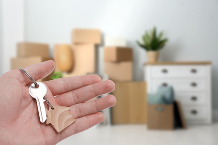 Real estate agent holding key indoors, closeup. Space for textの写真素材