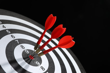 Targeting. Dart board with arrows on black background, closeup