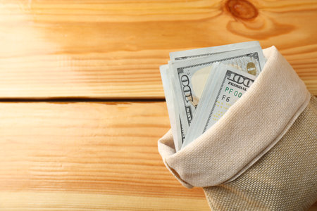Money bag with dollar banknotes on wooden table, top view. Space for textの写真素材