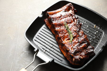 Delicious roasted pork ribs with rosemary on grey table, closeupの写真素材