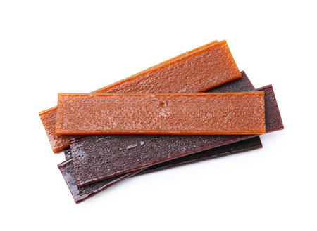 Pieces of delicious fruit leather on white background, top view