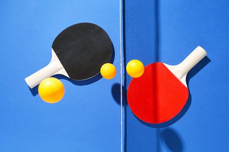Ping pong rackets, balls and net on blue background, flat lay