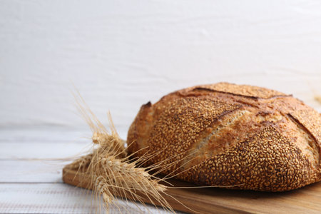 Fresh bread and spikes on white wooden table, closeup. Space for text
