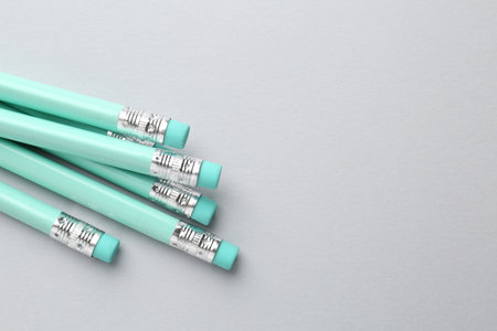 Many graphite pencils with erasers on light grey background, flat lay. Space for textの写真素材