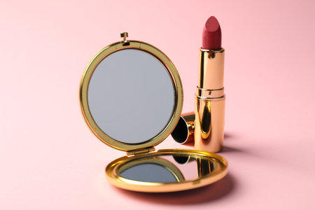Open pocket mirror and lipstick on pink background, closeupの写真素材