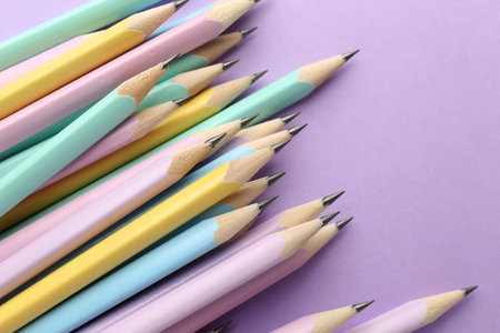 Many graphite pencils on violet background, flat lay. Space for text