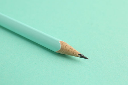 One graphite pencil on turquoise background, closeup