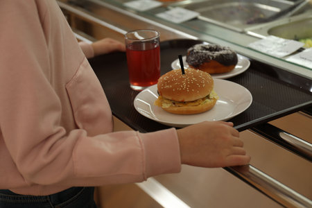 Little girl with plastic tray near serving line in canteen, closeup. School foodの写真素材