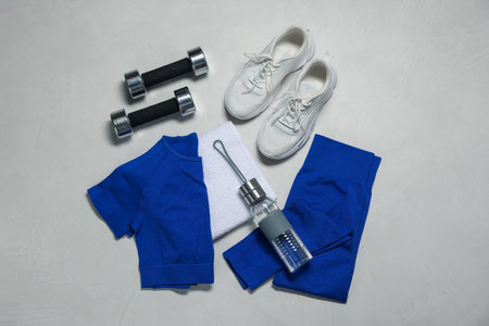 Sportswear, sneakers, dumbbells, towel and water bottle on gray textured background, flat layの写真素材